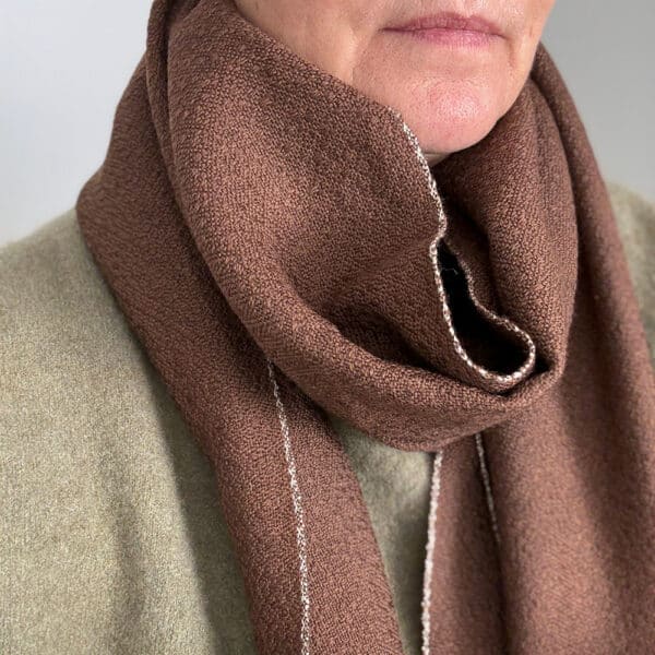 Ekslusivt håndvævet brunt tørklæde i merinould. Det er vævet brunt i brun ti et smukt mønster med lyse kanter der giver tørklædet karakter.