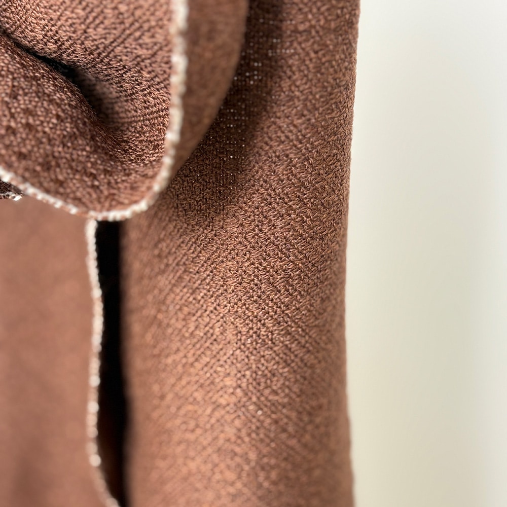 Ekslusivt håndvævet brunt tørklæde i merinould. Det er vævet brunt i brun ti et smukt mønster med lyse kanter der giver tørklædet karakter.