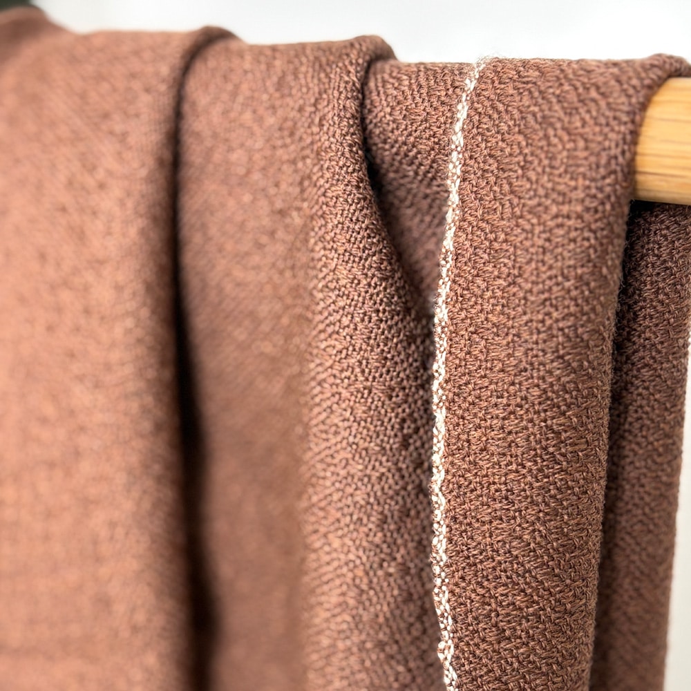 Ekslusivt håndvævet brunt tørklæde i merinould. Det er vævet brunt i brun ti et smukt mønster med lyse kanter der giver tørklædet karakter.